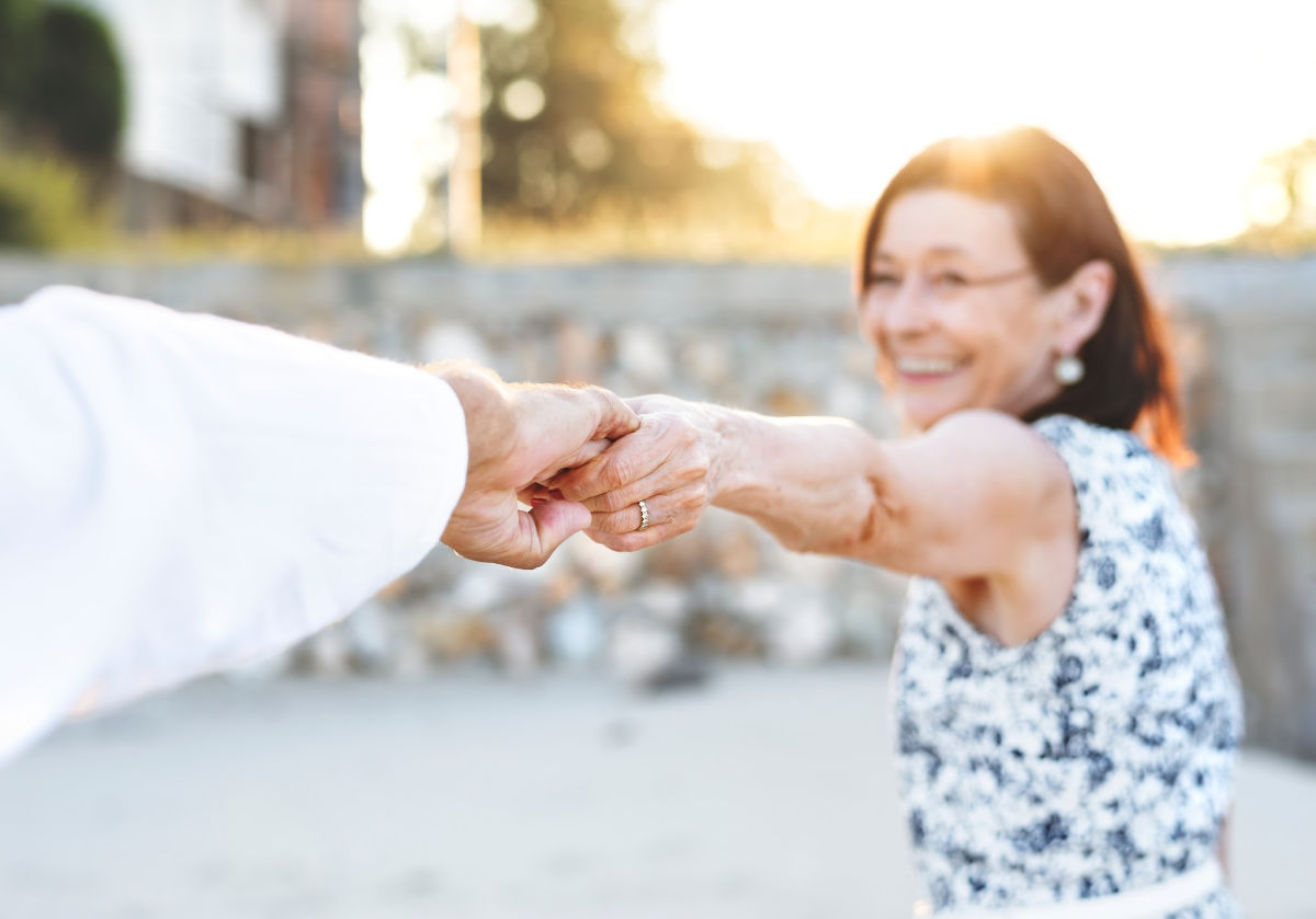 A Smiling Woman Holds a Man's Hand.