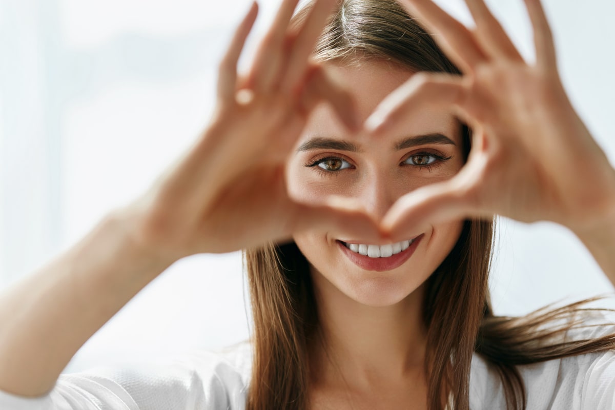 Beautiful Happy Woman Showing Love Sign in Front of Her Eyes.